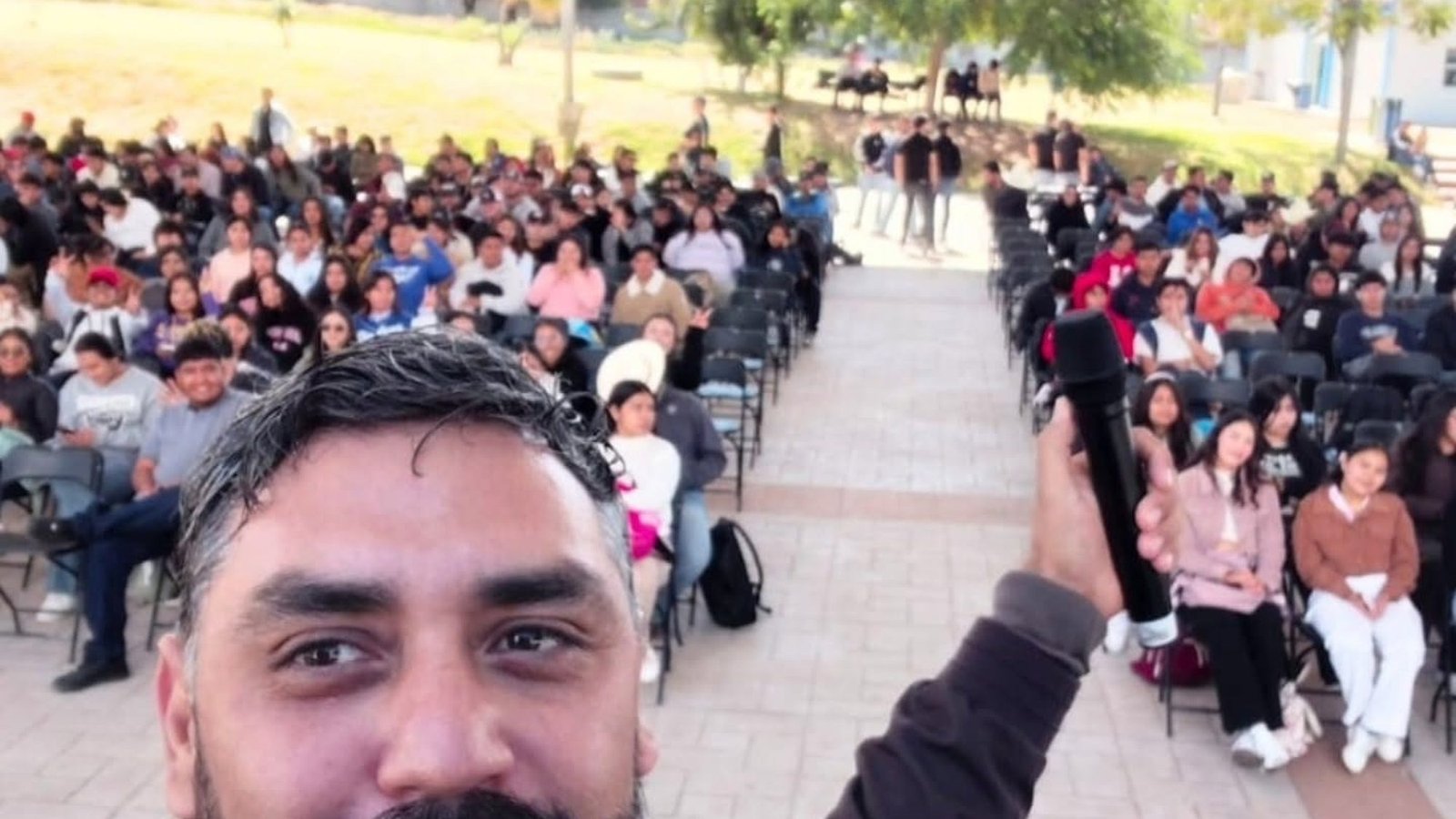 Iván Velázquez frente a cientos de asistentes en conferencia al aire libre.